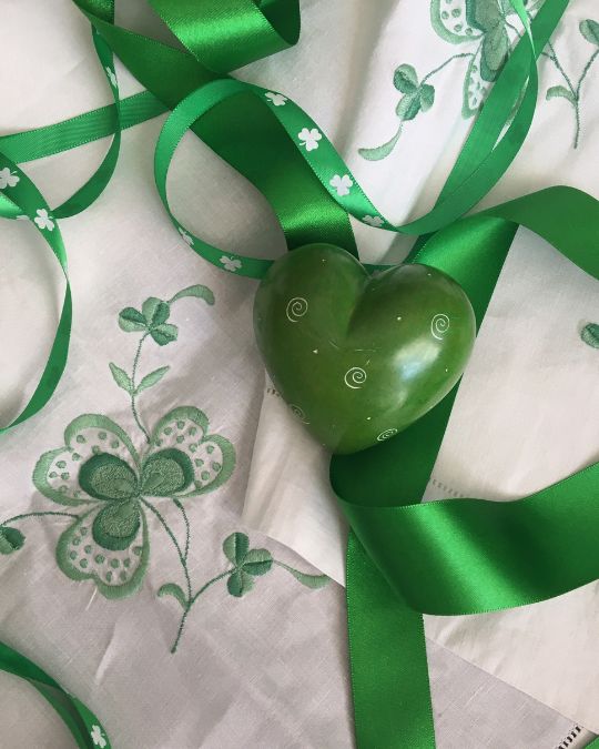 Irish linen tablecloth hand-embroidered with
shamrocks together with green ribbon, shamrock
printed ribbon, and a green stone heart