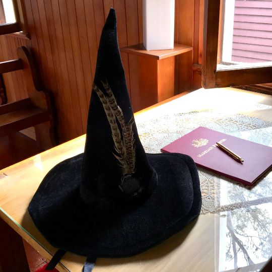 Signing
table next to an open window. On the table is the
marriage register, a gold pen, and Professor
McGonagall's hat
