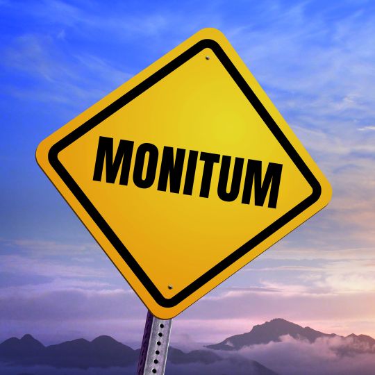 Road sign with
the word Monitum on it photographed against a
sunrise sky