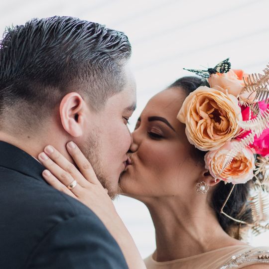 Couple kissing. She
is wearing a gold wedding ring and roses in her
hair