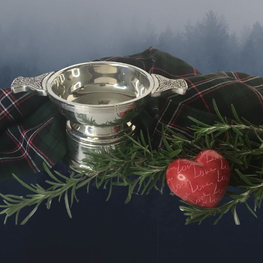 A silver
                      quaich with a sprig of rosemary, and red
                      heart-shaped stone that has the word Love repeated
                      over its surface and a length of the Scottish
                      National Tartan, on a white background