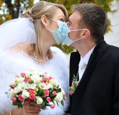 Bride and Groom kissing wearing surgical
masks