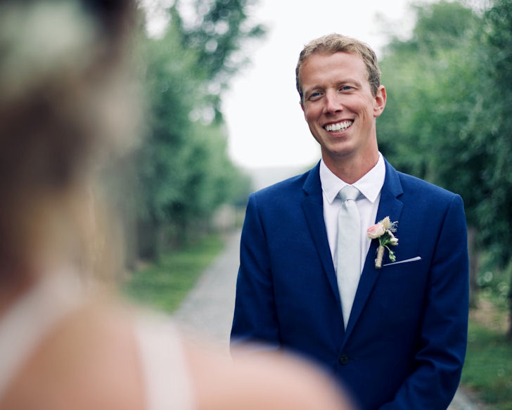 Bridegroom wearing
blue suit smiling at out-of-focus bride
